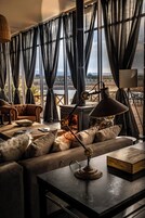 Un salón acogedor con chimenea, asientos cómodos y grandes ventanales con vistas panorámicas.