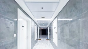 A modern hotel corridor with marble flooring, glass doors, and a clean, minimalist design. - Spacious Studio With Balcony in AL Majan (Dubai)
