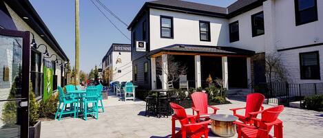 A hotel with outdoor seating, a patio, and a clear sky.