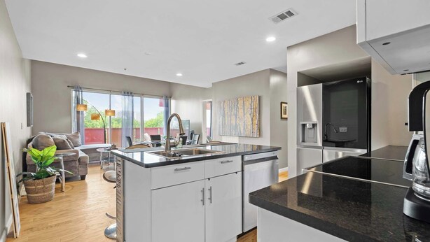 A modern kitchen with a central island, stainless steel appliances, and a dining area with a view.
