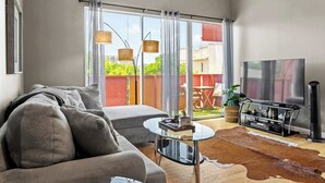 A modern living room with a sofa, a glass coffee table, a flat-screen TV, and a fireplace.