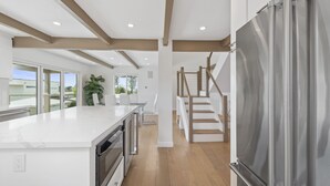 Een moderne keuken met een groot kookeiland, een inbouwoven en een roestvrijstalen koelkast.