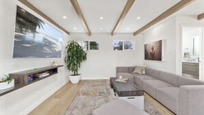 Een moderne woonkamer met een groot raam, een bank, een salontafel en een boekenkast.