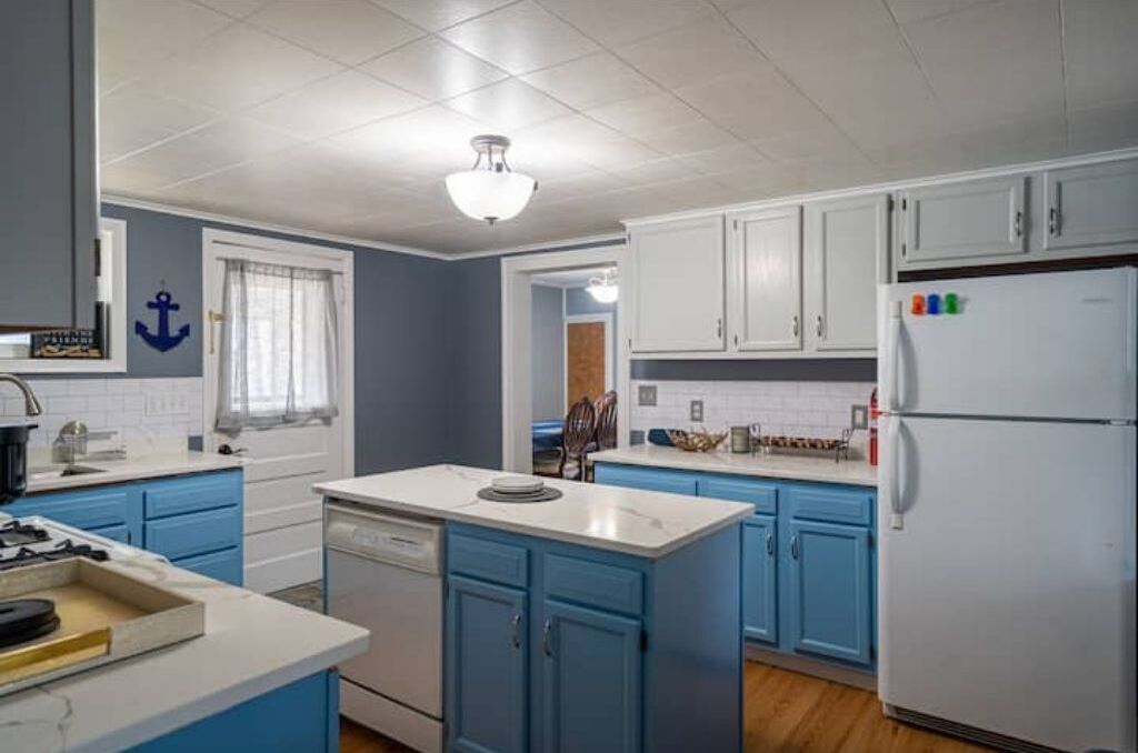 A kitchen with blue cabinets, a white refrigerator, and a stove.