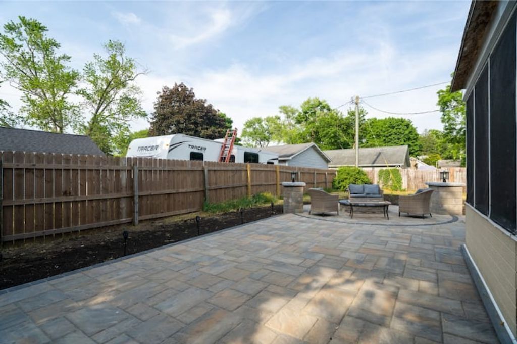 Eine Terrassenfläche mit Steinplatten, einem Holzzaun und Gartenmöbeln.