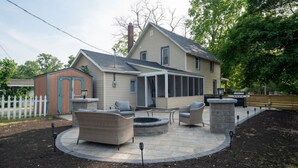 Une maison dotée d’un patio couvert, aménagé avec du mobilier d’extérieur et un foyer.