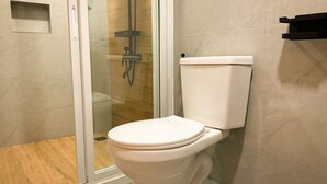 Ein modernes Badezimmer mit Toilette, einer Duschkabine aus Glas und Holzboden.