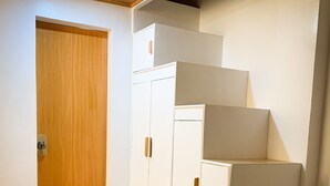 Ein Zimmer mit Holztür, weißem Kleiderschrank und einer Holztreppe.