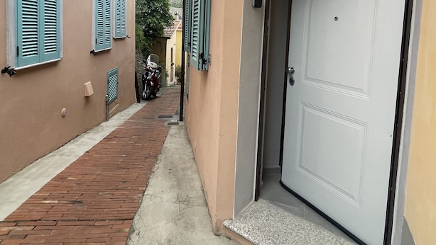A narrow alleyway with a building featuring a white door and a small porch. - Pretty Studio Flat Moglio Alassio (Moglio)