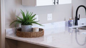 A kitchen counter with a potted plant, a candle, and a bottle of soap. - The Bee, Cozy 1BR Studio by Velvet Ditch Villas (Oxford)