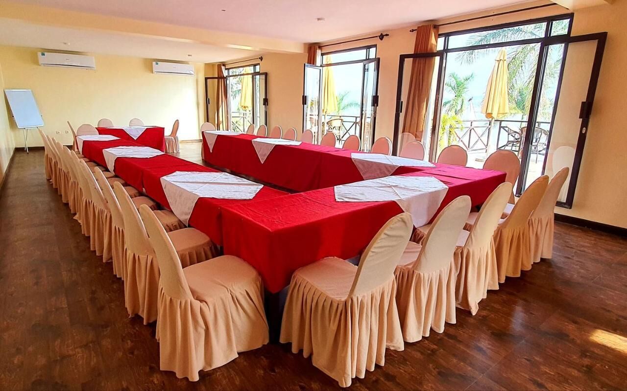 A conference room with multiple tables and chairs, large windows with curtains, and a whiteboard.