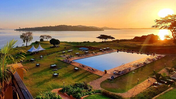 Ein Resort mit großem Pool, Sitzgelegenheiten im Freien und Blick auf den Sonnenuntergang über dem Wasser.