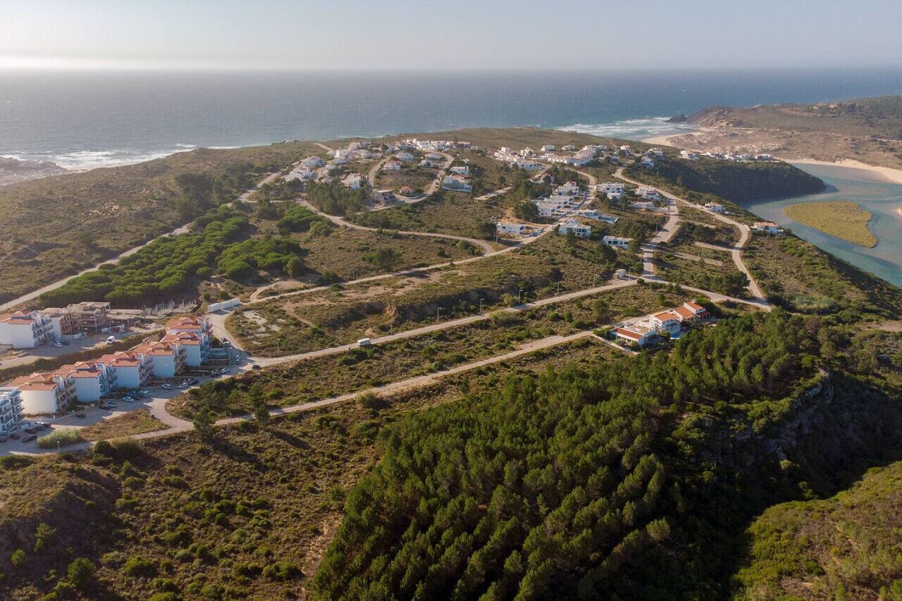 An aerial view of a coastal resort with multiple buildings, roads, and a beach.