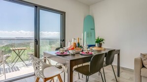 En matplats med ett bord dukat för två personer, en surfbräda och utsikt över landskapet.