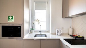 Et moderne køkken med indbygget mikroovn, vask, et vindue med naturligt lys og en elkedel.