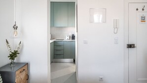 A modern kitchen with light green cabinets, a white countertop, and a hanging light fixture. - Studio in Central Lisbon by Lisbeyond (Lisboa)