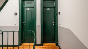Two green doors labeled 2E and 2D, a wooden staircase, and a metal handrail. - Studio in Central Lisbon by Lisbeyond (Lisboa)