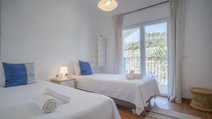A hotel room with two beds, a balcony, and a view of the outdoors. - Beach & Nature Apartmentn in Aljezur by Lisbeyond (Aljezur)