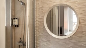 A shower with a handheld showerhead and a handheld shower attachment, a round mirror on the wall, and a geometric patterned wall. - Studio with Stunning Views to river and old town by Lisbeyond (Lisboa)