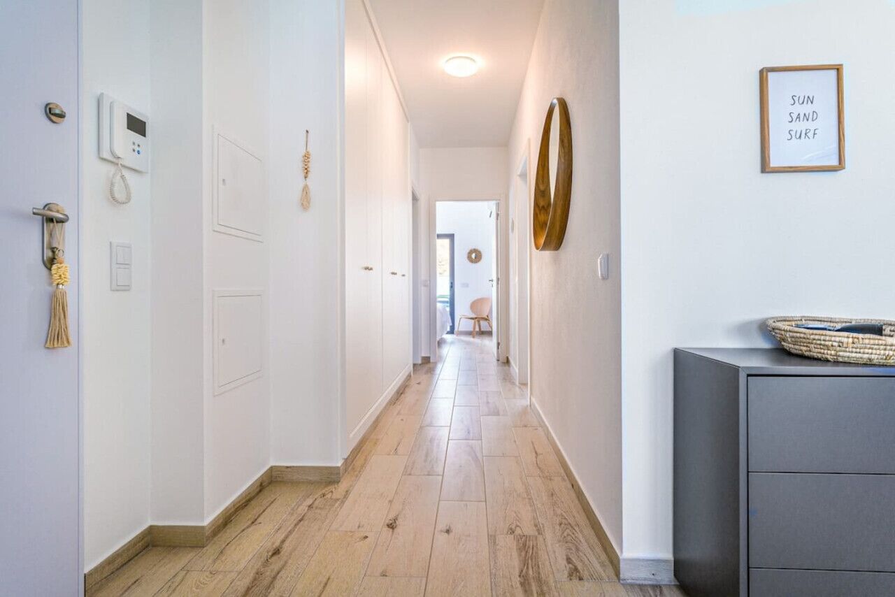 A hallway with a wooden floor, a wall-mounted phone, and a framed sign.