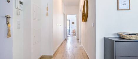 A hallway with a wooden floor, a wall-mounted phone, and a framed sign.