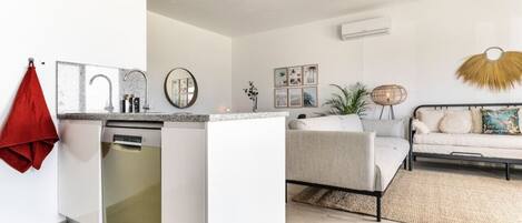 Una cocina moderna con lavavajillas, una pequeña isla y una toalla roja colgada en la pared.