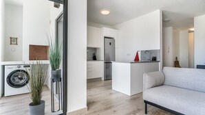 A modern apartment with a living room, kitchen, and laundry area. - Sun, Sand & Surf Apt in Aljezur by Lisbeyond (Aljezur)
