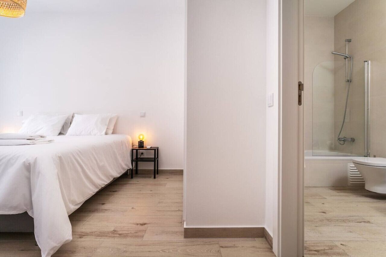 Un dormitorio con cama, mesita de noche y una lámpara.