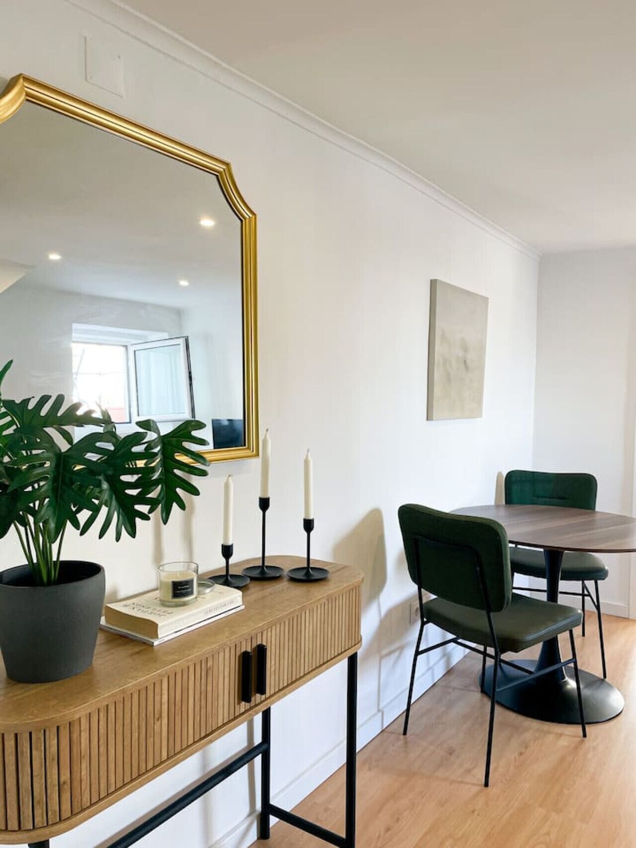 Un espace repas moderne avec une console en bois, un fauteuil recouvert d’un tissu vert et une table ronde.