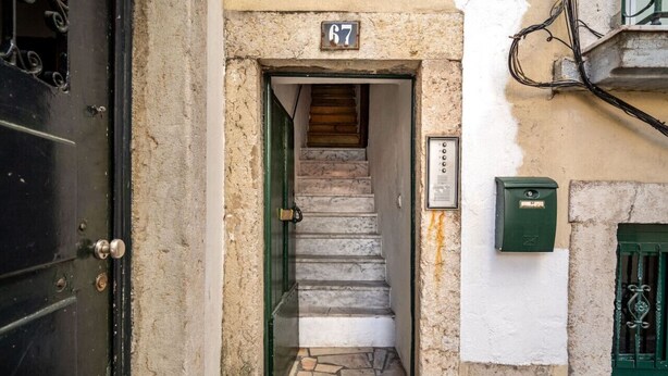 A narrow stairway leading to a door marked with the number 67, a mailbox, and a green door. - Stay in the heart of Alfama! | Cozy Apartment (Lisboa)