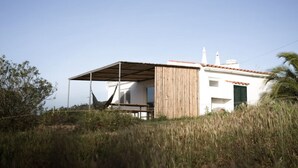 Un petit bâtiment d’un seul étage, doté d’un toit en pente, d’un espace extérieur abrité et d’un hamac.