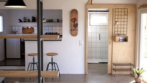 Une cuisine moderne avec un plan de travail en bois, des tabourets et une planche en bois suspendue ornée d’un motif solaire.