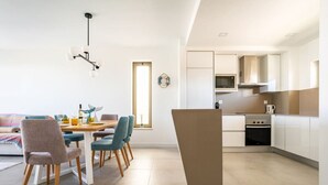 A modern kitchen with white cabinets, a built-in microwave, and a stove. - Oasis Mar Beach Apartment by Lisbeyond (Portimão)