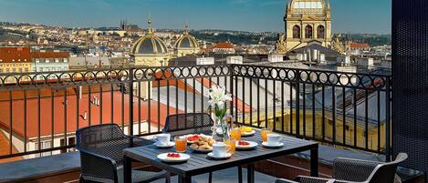 A balcony with a table set for breakfast, overlooking a cityscape with domed buildings and a large church.
