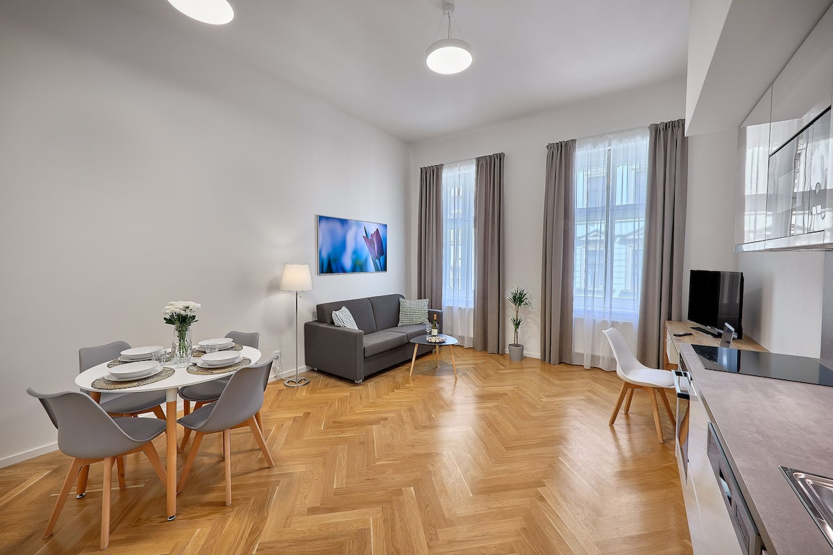 A modern living room with a sofa, dining table, and a TV.