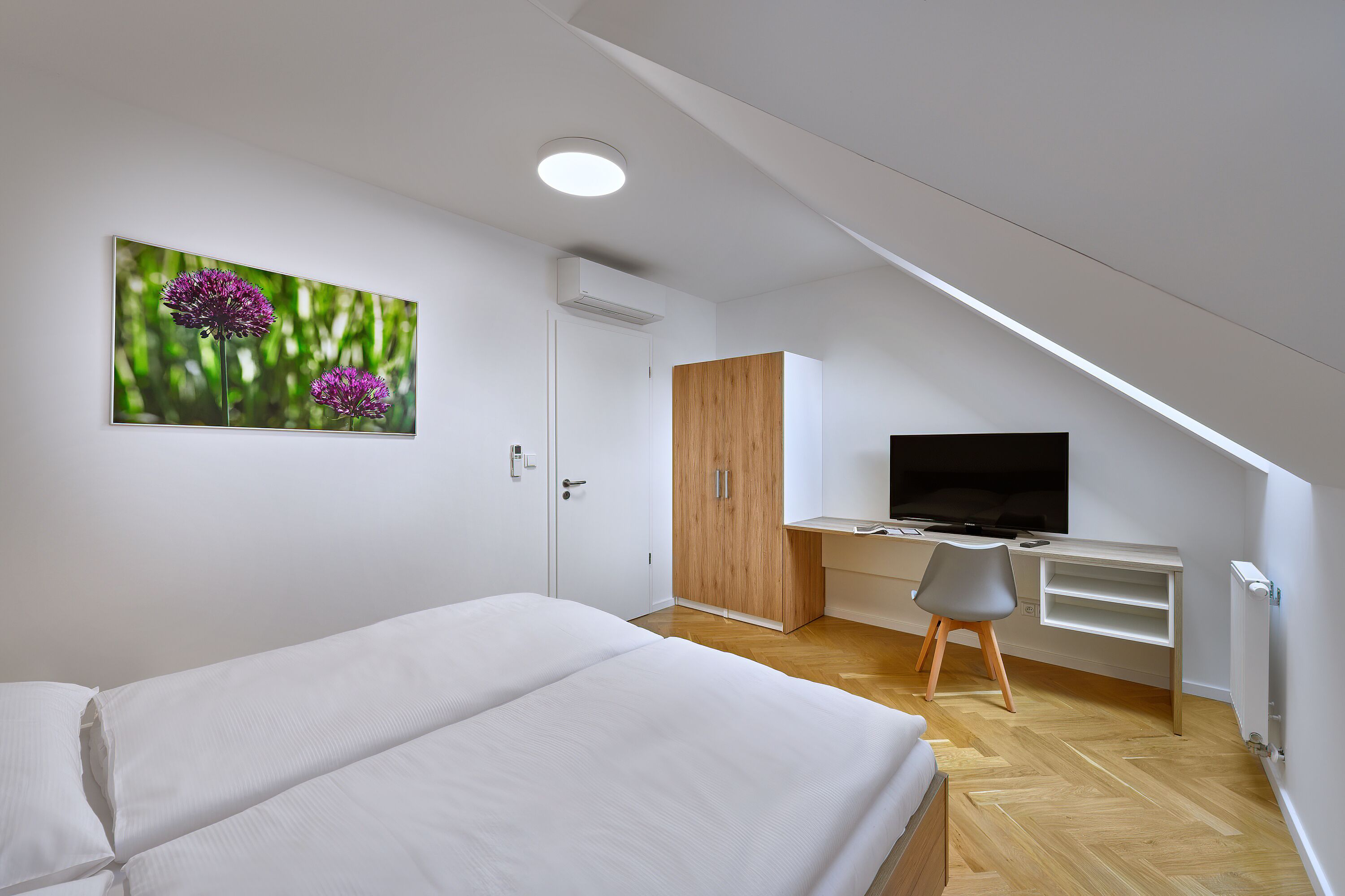 Un dormitorio con cama, escritorio con televisor y armario.
