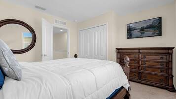 A bedroom with a bed, a dresser, a mirror, and a painting on the wall.