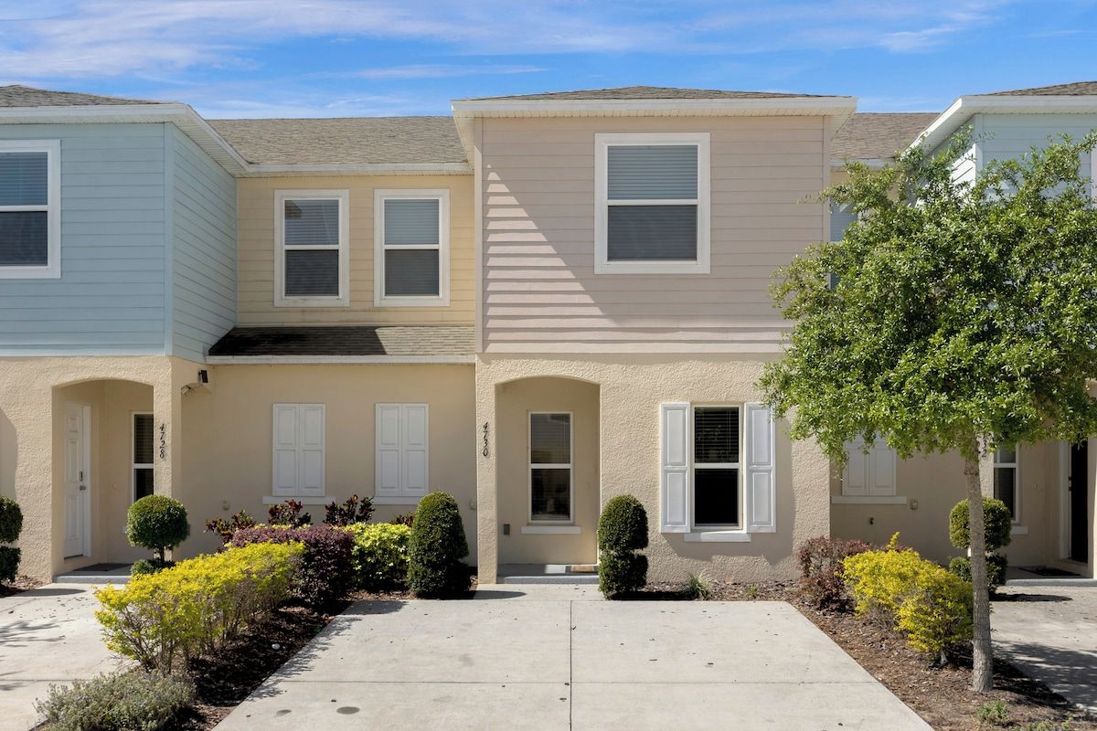 A row of townhouses with a central entrance, small front yards, and a clear sky.