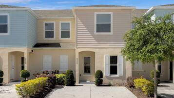 A row of townhouses with a central entrance, small front yards, and a clear sky.