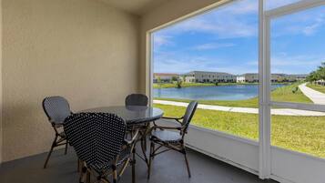 A balcony with a table and chairs, overlooking a body of water and buildings.