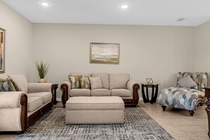 A living room with a sofa set, ottoman, and a patterned rug. - 4730 Lakeview Townhome with Pool Access Near Disney (Kissimmee)