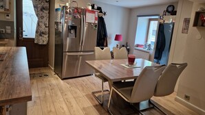 Ett modernt kök med ett kylskåp i rostfritt stål, ett matbord och stolar i trä.