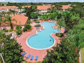 A resort with a large swimming pool, lounge chairs, and a well-maintained garden. - 4732 Lakeview Townhome Near Disney Gym Access (Kissimmee)
