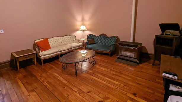 Un salon avec un plancher en bois, deux canapés, une table et une cheminée.