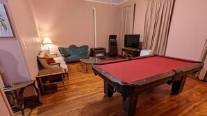 Une pièce équipée d’une table de billard, d’un canapé, d’une télévision et d’une lampe.