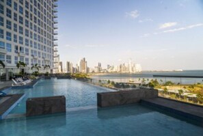 A hotel pool with a city skyline and ocean view.