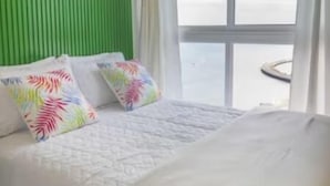 A hotel room with a large bed, a green accent wall, and a view of the sea. - studio apartment - ocean view (Panamá)