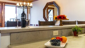 En køkkenbordplade med en vinflaske, glas, en skål med frugt og et spejl.