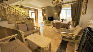 A spacious living room with a staircase, a dining area, and a television. - Marrone Hotel Tsaghkadzor (Tsaghkadzor)