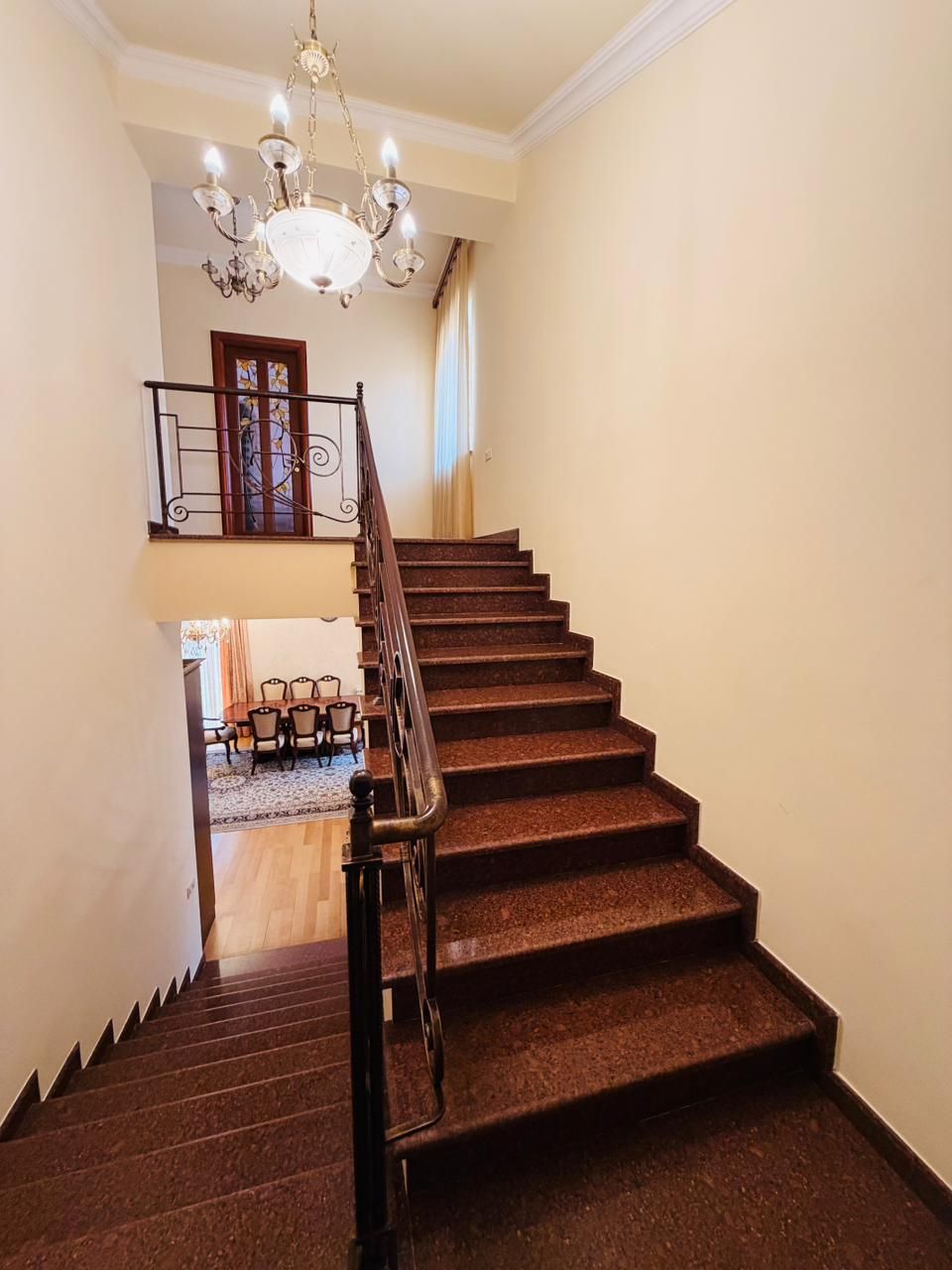 A staircase with a wooden handrail and a chandelier.